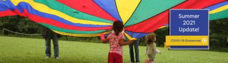 kids playing under brightly colored parachute